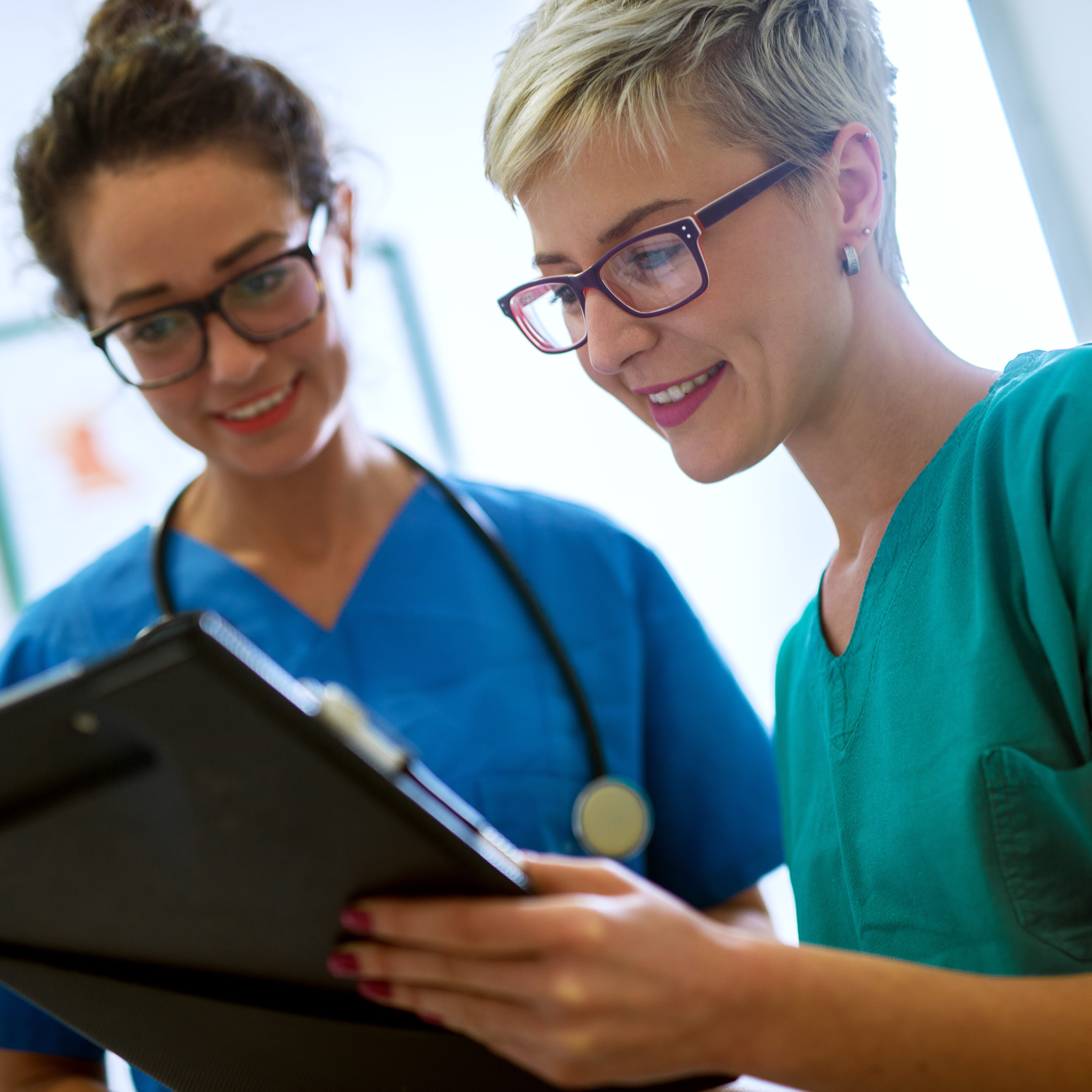 Close up view of two professional nurses with eyeglasses checking the patient papers in a doctors office.
